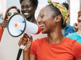 Photo focused on a young woman, smiling, with a megaphone.