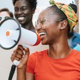 Photo focused on a young woman, smiling, with a megaphone.