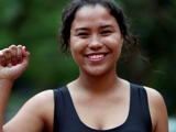 Photo of a young woman smiling, holding up her right hand in a fist.