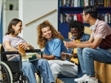Photo of 4 young people in a college sitting and talking.