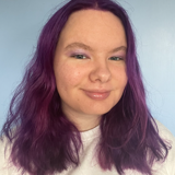 Photo of person with purple hair smiling at camera