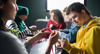 Photo of a group of people with learning disabilities doing arts and crafts projects, focused in on a young man, smiling. 