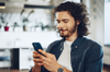 Man holding and looking at his mobile phone, with a blurred background