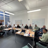 Photo of workshop participants sitting around table and smiling