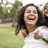 A woman giving a piggyback to a child, both smiling.