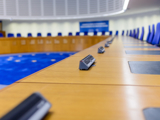 Photo of the inside of the European Court of Human Rights (empty), with the view looking down the desks the judges are at.