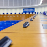 Photo of the inside of the European Court of Human Rights (empty), with the view looking down the desks the judges are at.