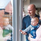 Photo of family in house smiling and looking out of glass door